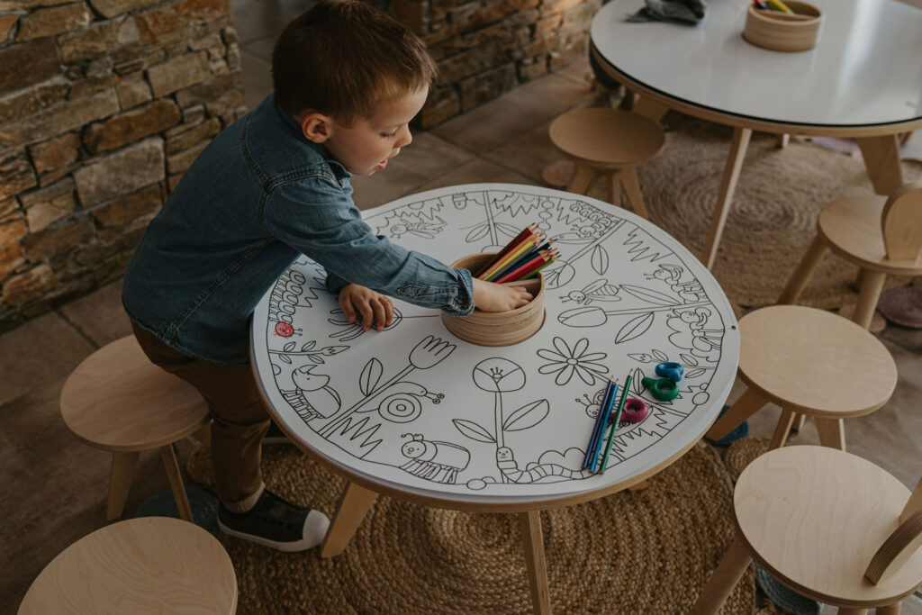 Enfant coloriant à une table ronde.