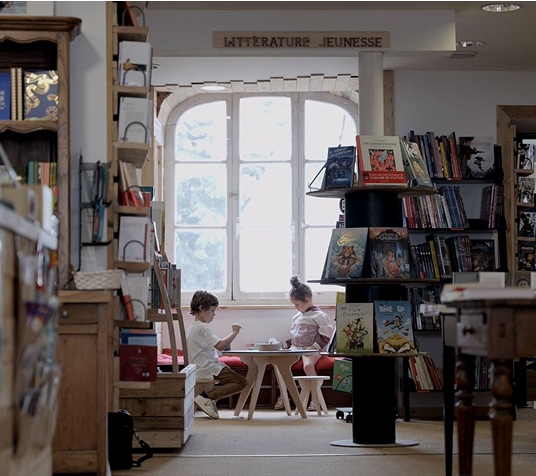 Table Drawin’table installée dans une librairie avec deux enfants autour