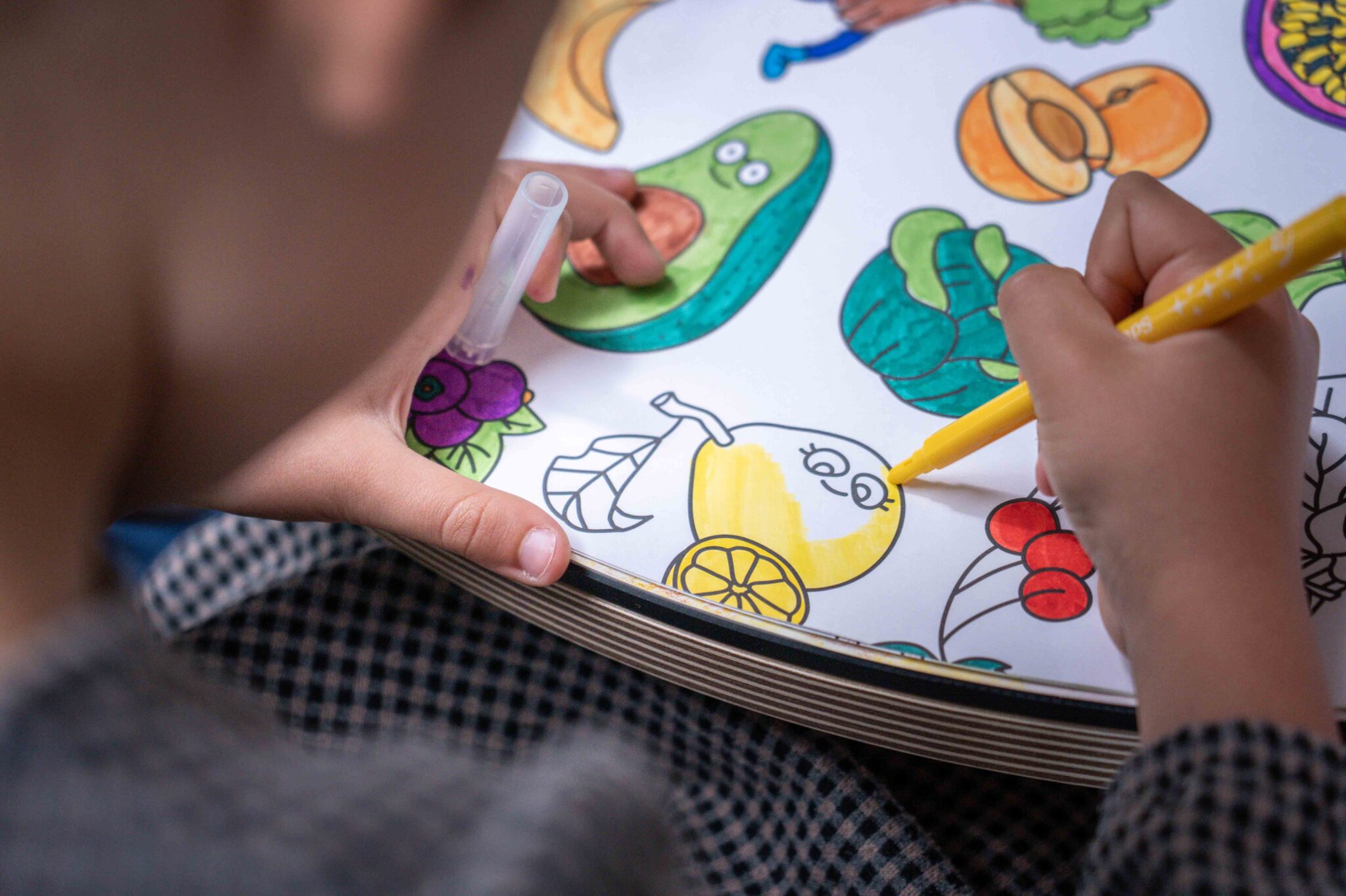 Child coloring fruit in a notebook