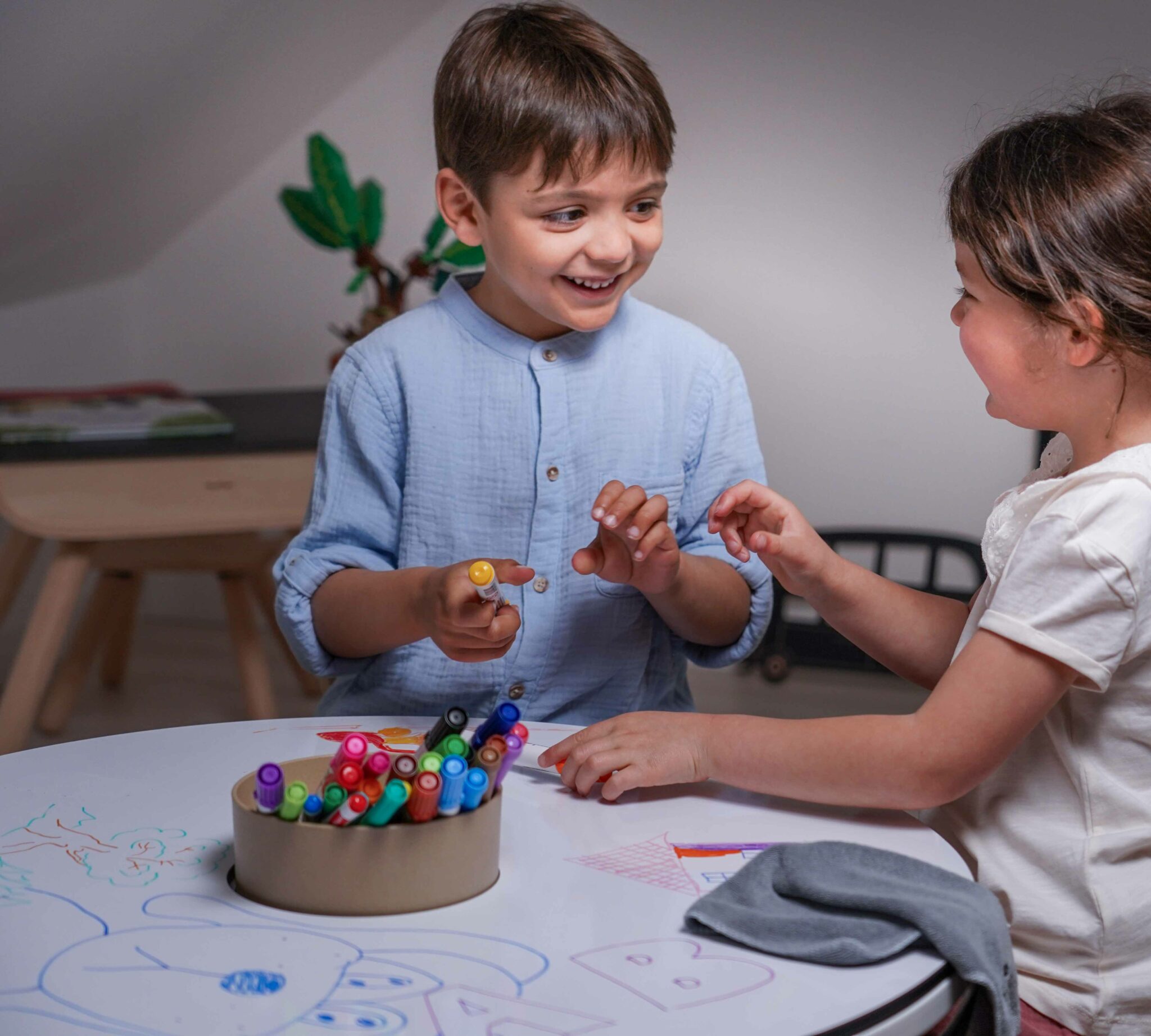 Deux enfants dessinant ensemble sur une table de coloriage Drawin’kids