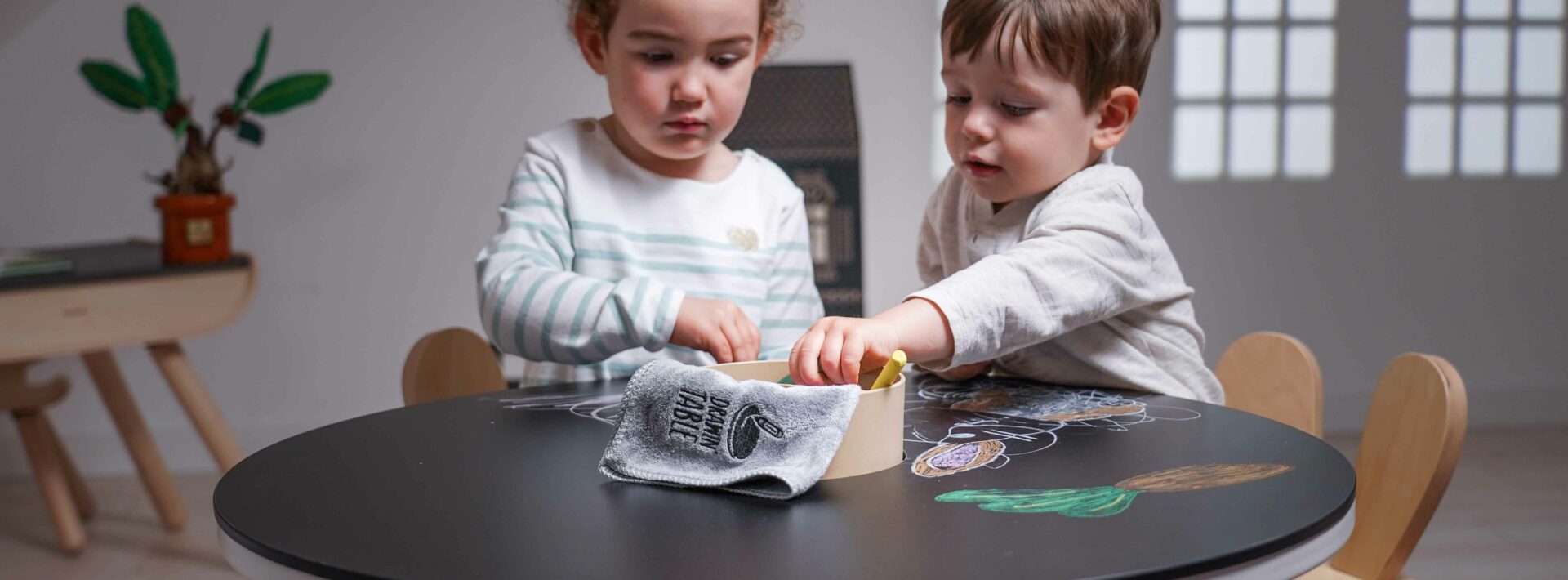 Deux jeunes enfants dessinent à une table ronde