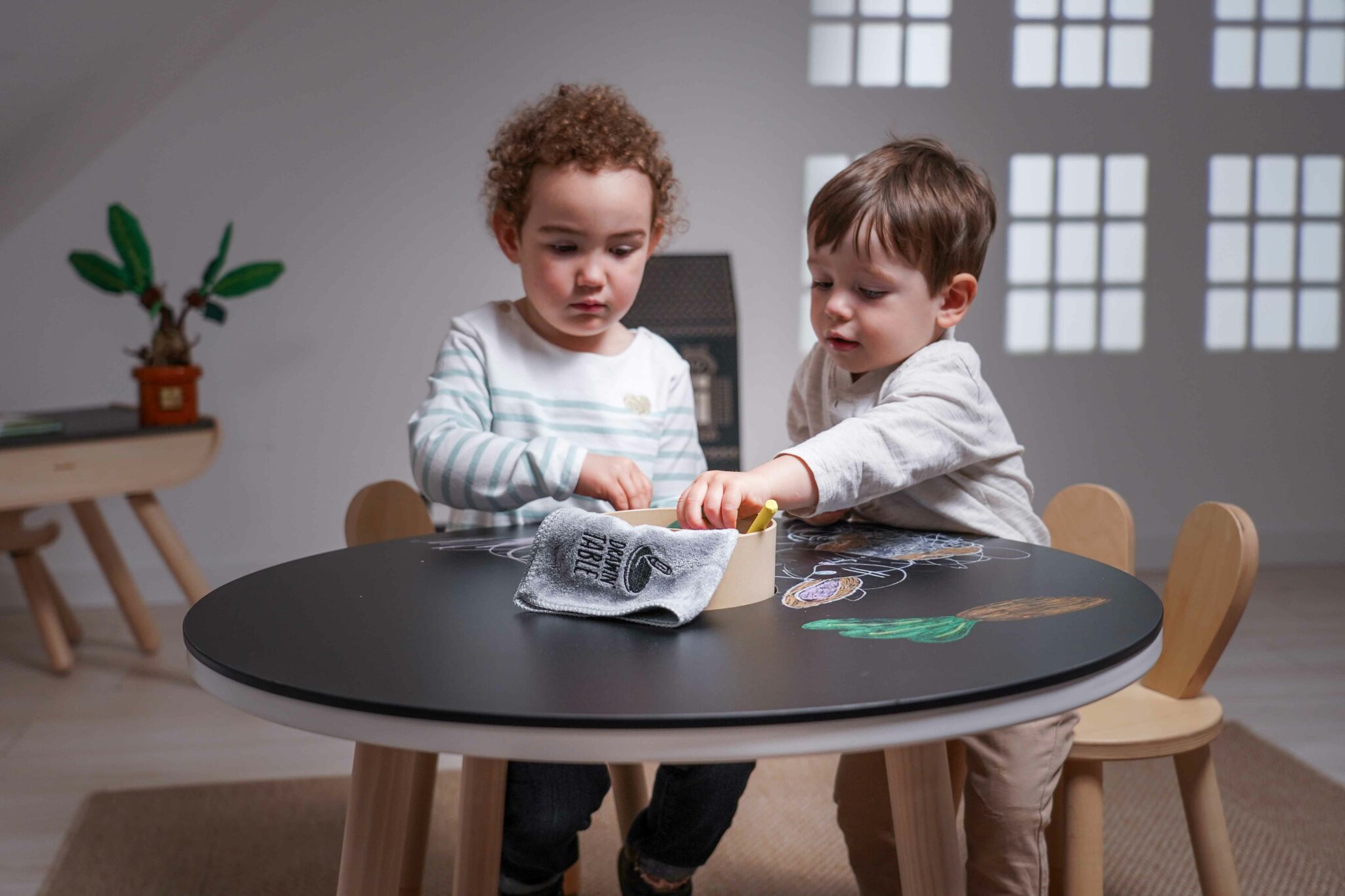 Deux jeunes enfants dessinent à une table ronde