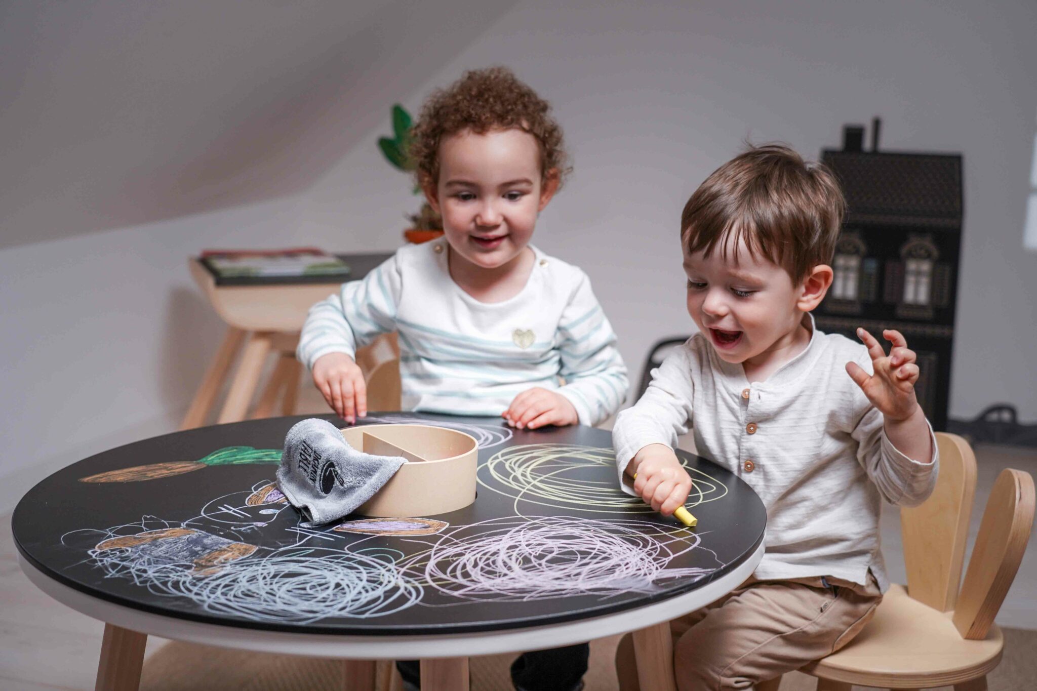 Deux enfants dessinant à la craie sur table