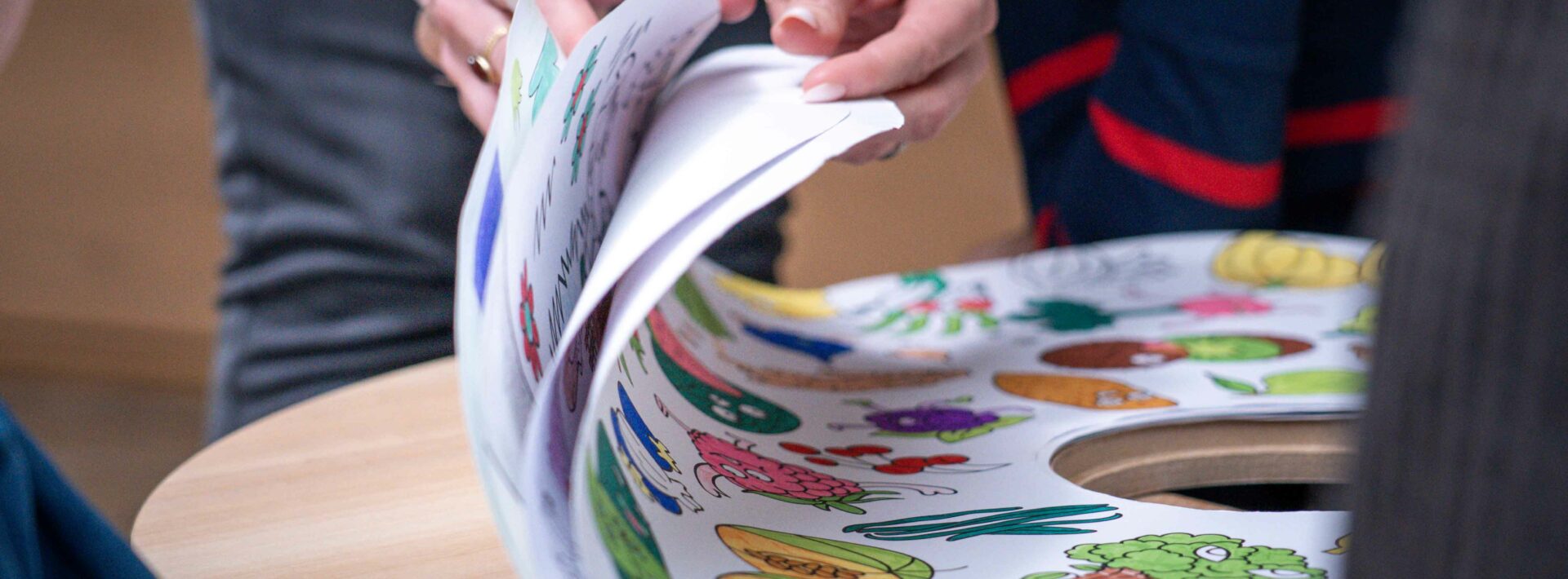 Hände, die durch ein farbenfrohes illustriertes Buch blättern