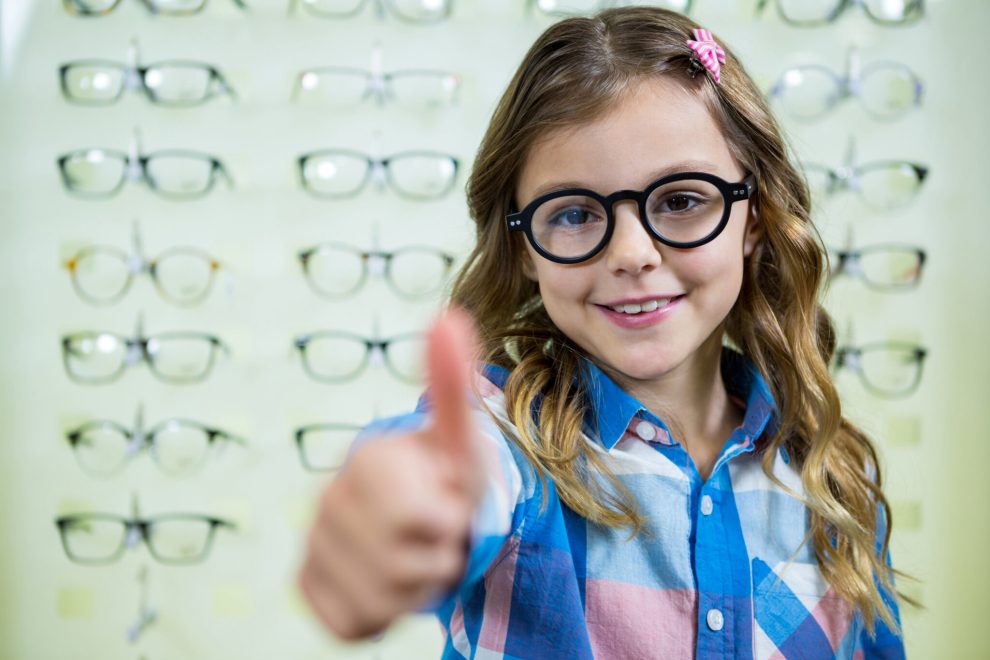 portrait of girl showing thumbs up in optical store Fille avec lunettes, pouce levé, opticien.